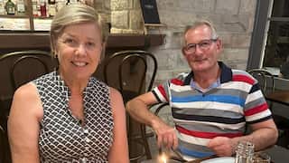 a middle aged couple - woman and man - smile sitting in a restaurant together