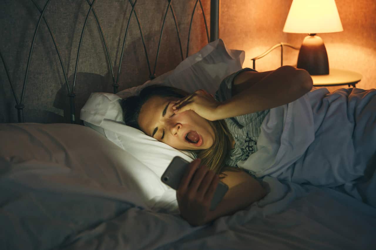 Girl with a cell phone yawns