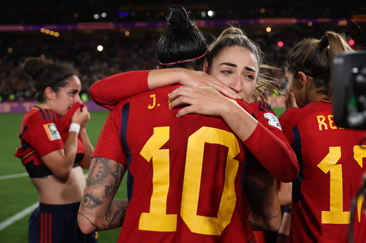 A group of football players in red jerseys embrace after winning.