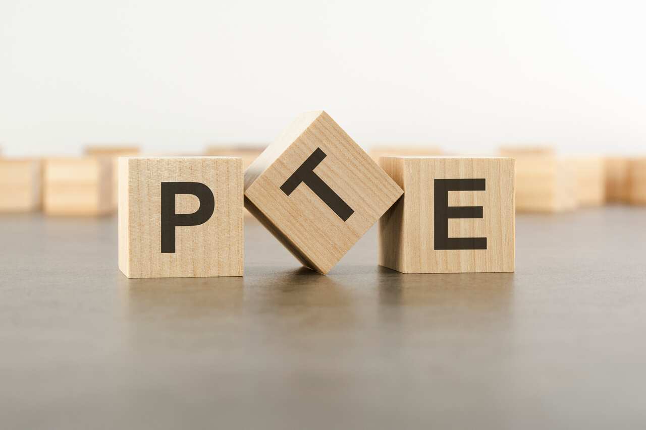 wooden cube with the letter from the PTE word. wooden cubes standing on gray background. PTE - short for Pearson Tests of English. 