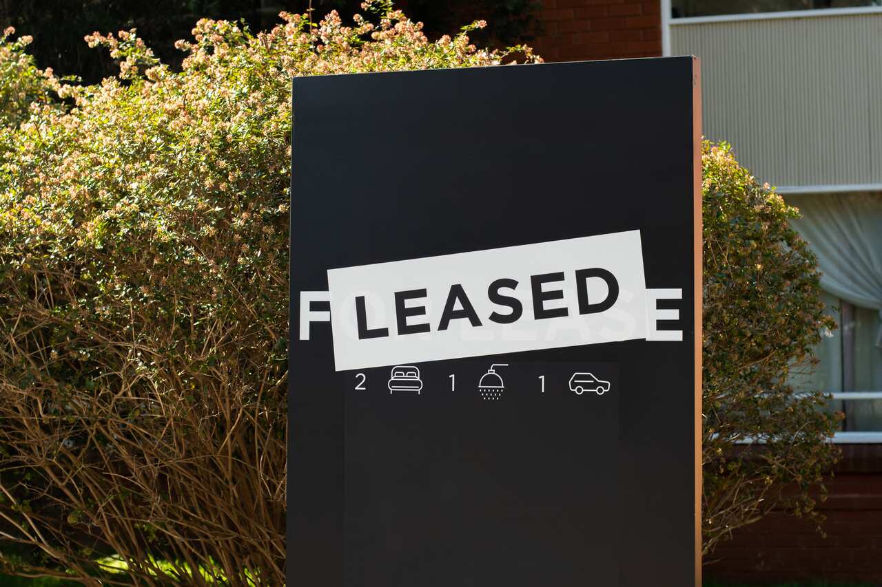 For lease and leased sign on a black display outside of a residential building