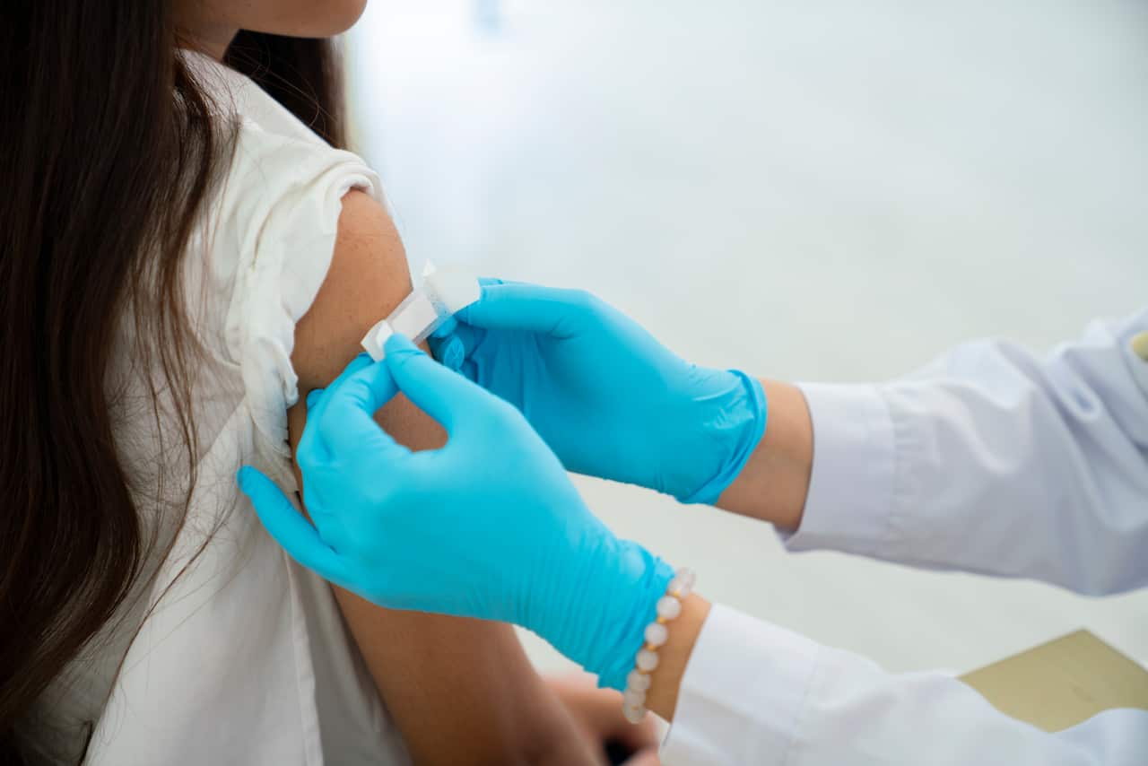 A doctor places a bandaid over a patient's arm
