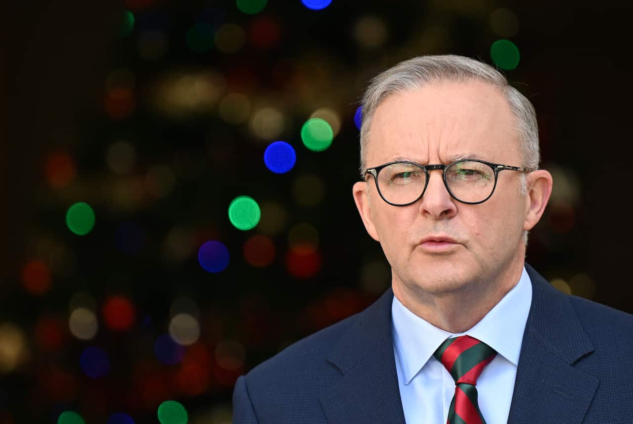 A man wearing a suit, tie and glasses who is speaking.