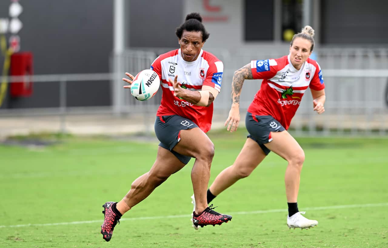 A woman running and about to catch a rugby league ball