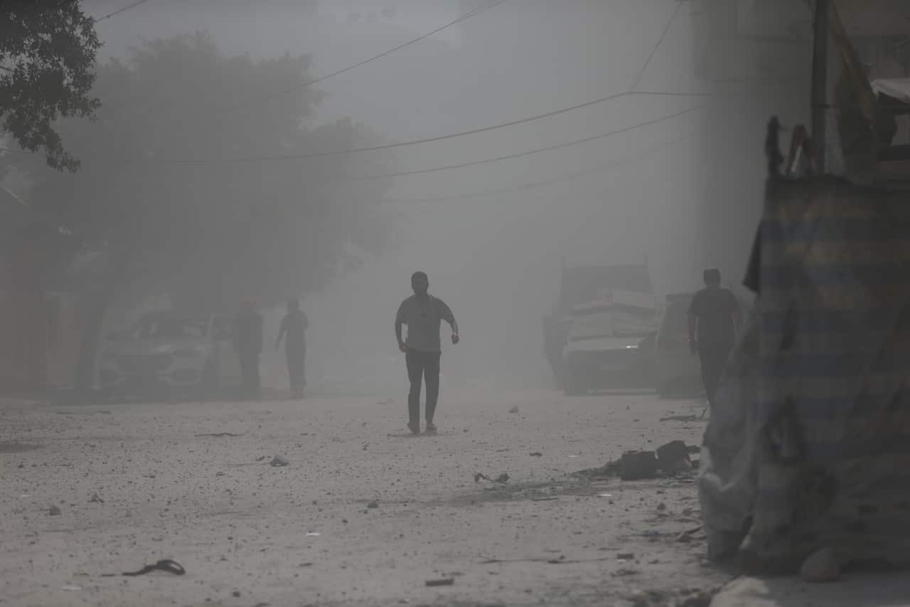  A silhouette of a man walking through dust on a street.