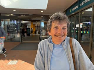 A smiling woman with short grey hair and wearing a grey cardigan