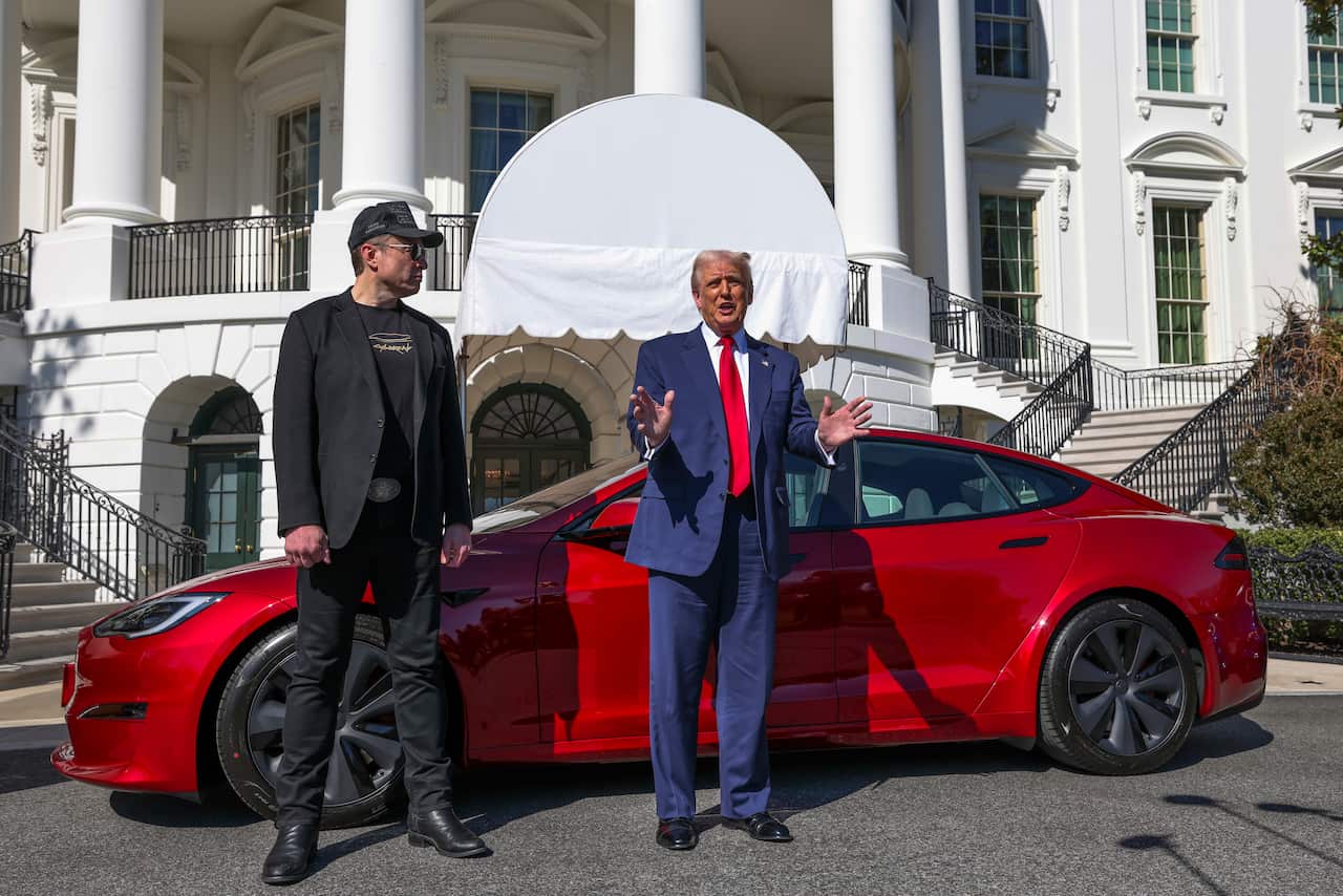 President Donald Trump and Tesla CEO Elon Musk speak to reporters in front of a red Model S Tesla vehicle on the South Lawn of the White House.