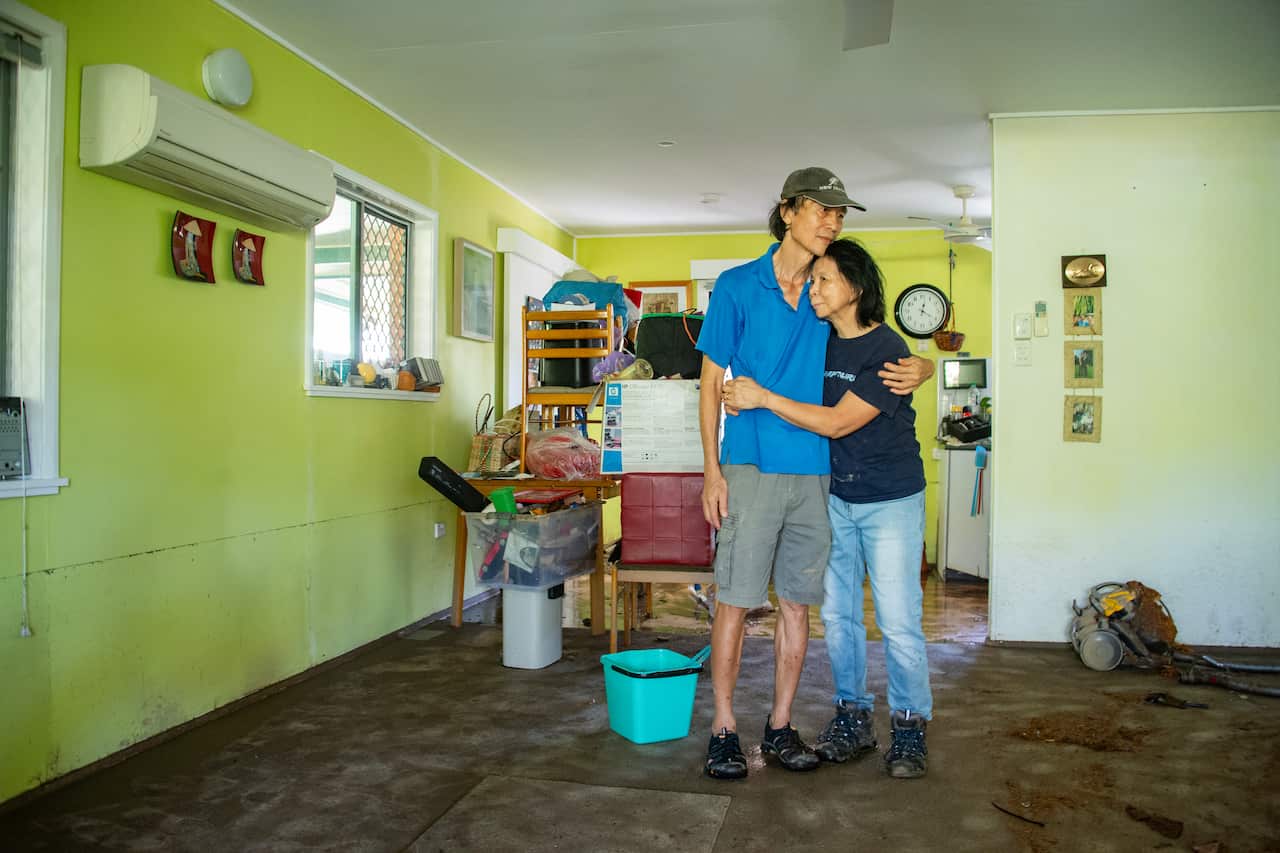 A couple embrace in a flood damaged house