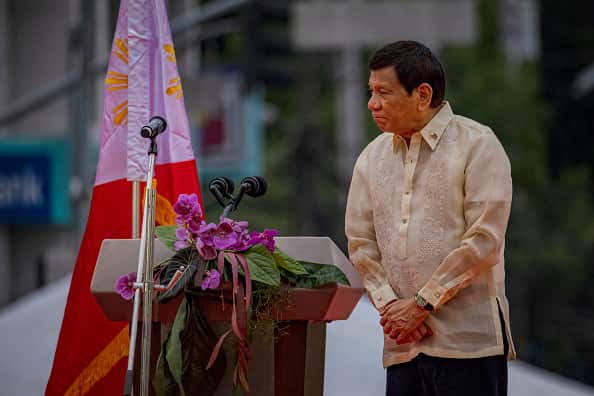 Rodrigo Duterte, wearing a cream-coloured shirt, stands next to a lectern