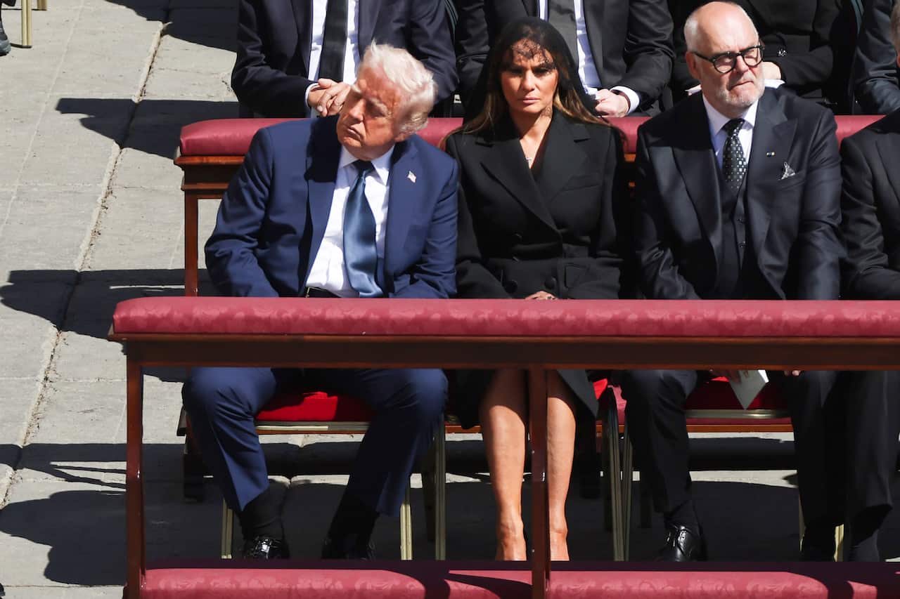 US President Donald Trump and First Lady Melania sitting on pews with velvet cushioning. 