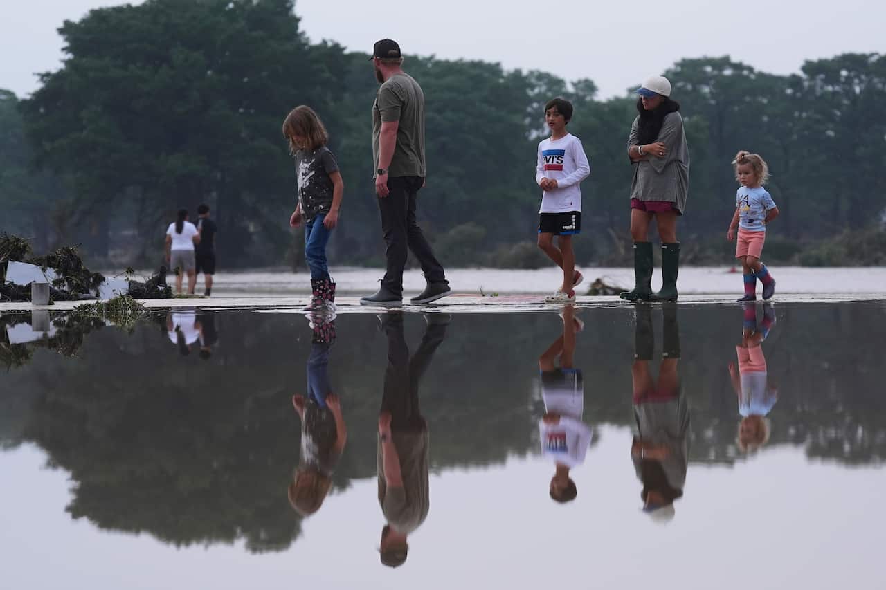 People survey damage along a river after flash flooding. 