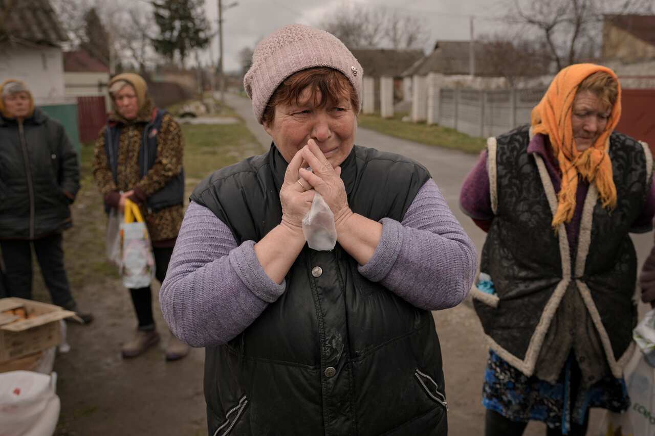 A woman is seen crying while waiting along with others for distribution of food products.