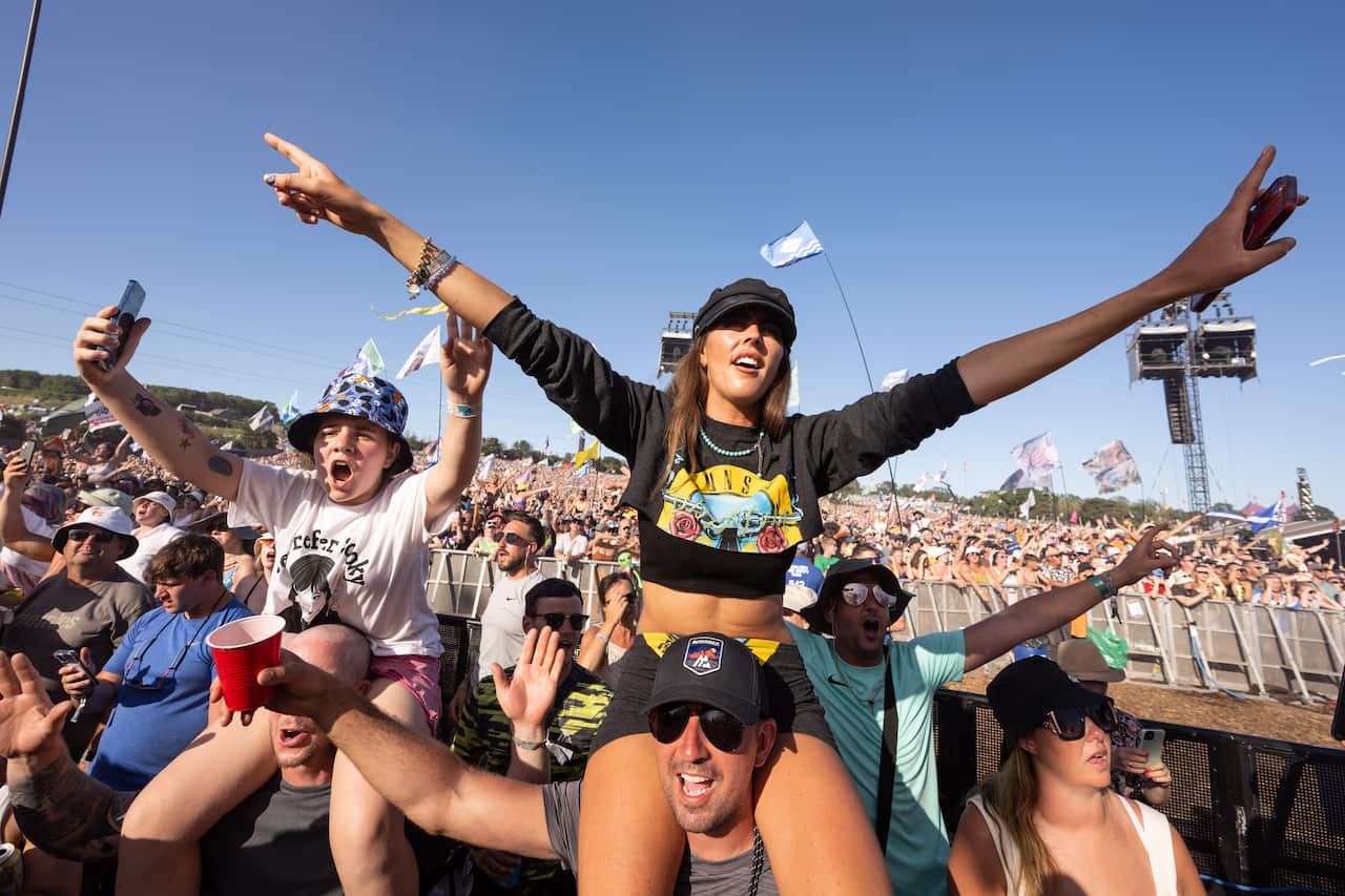 A crowd at a music festival singing and cheering.