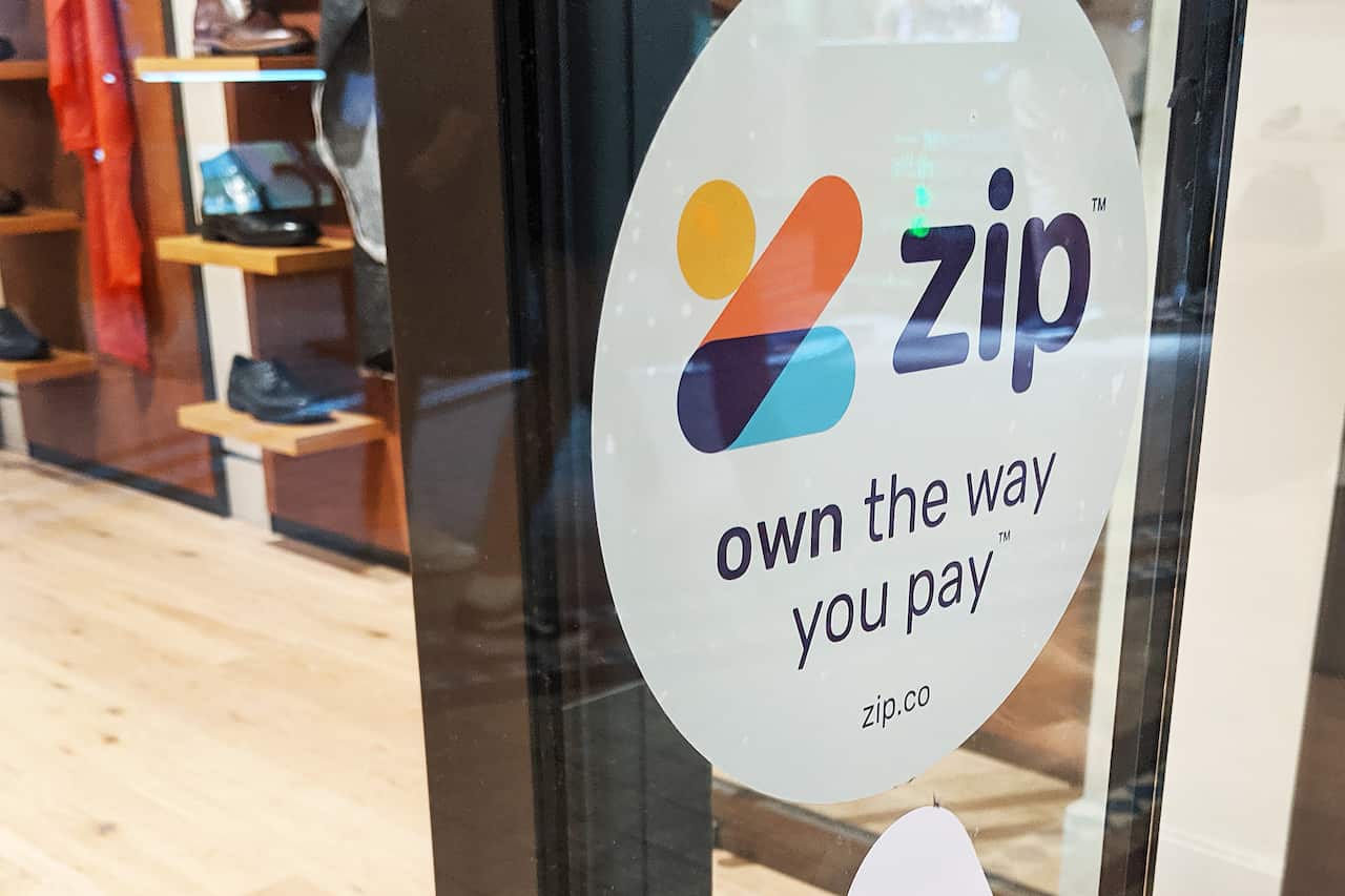 A window at a shop that has a sticker attached that reads: "Zip: Own the way you pay."