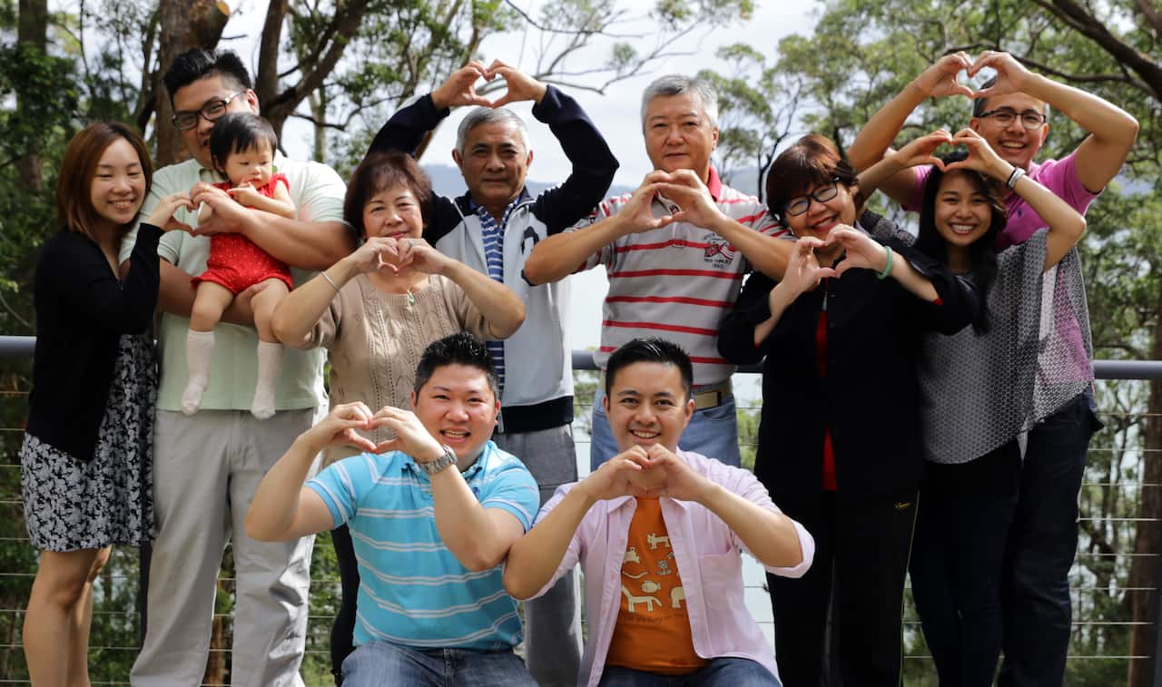 A group of people hold their hands in love heart shape.